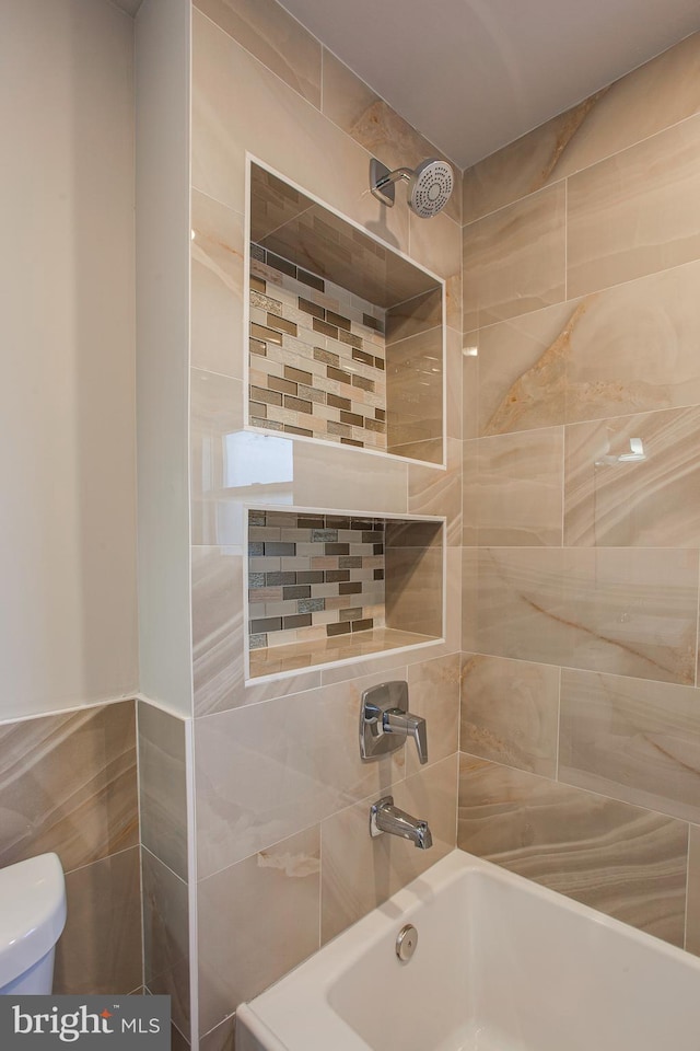 bathroom featuring tiled shower / bath combo and toilet