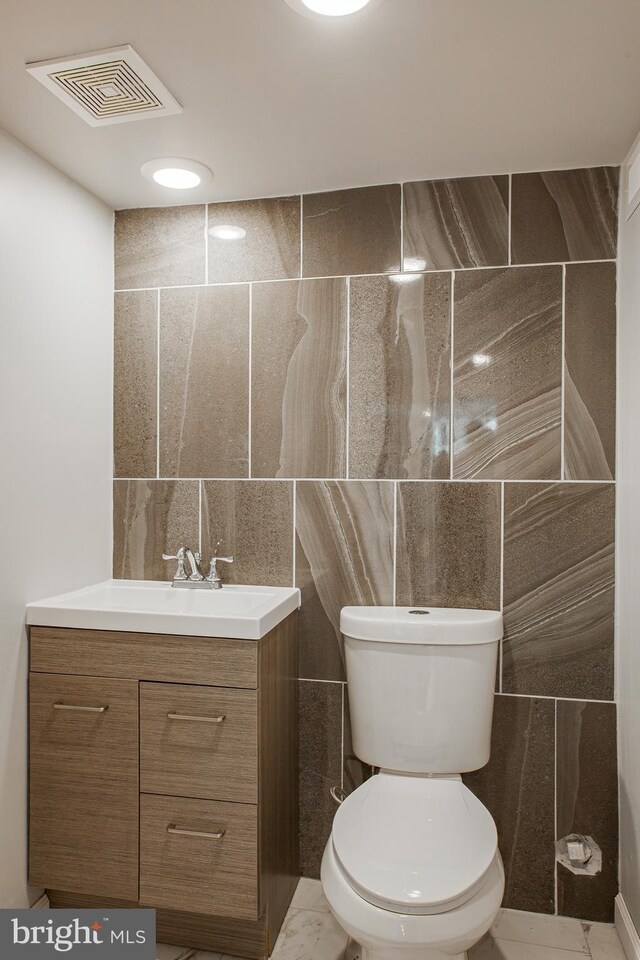 bathroom with tile walls, tile patterned floors, and toilet