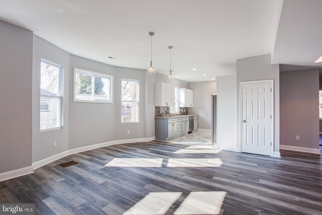 unfurnished living room featuring plenty of natural light and dark wood-type flooring