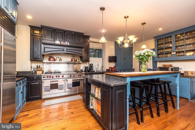 kitchen featuring a breakfast bar, high quality appliances, a kitchen island, pendant lighting, and dark stone counters