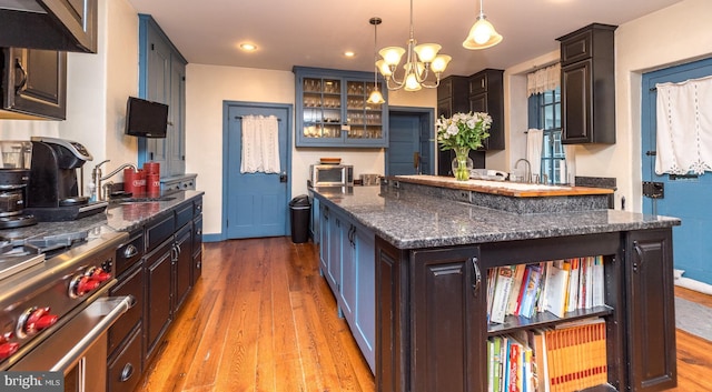 kitchen featuring a center island, sink, dark brown cabinets, and decorative light fixtures