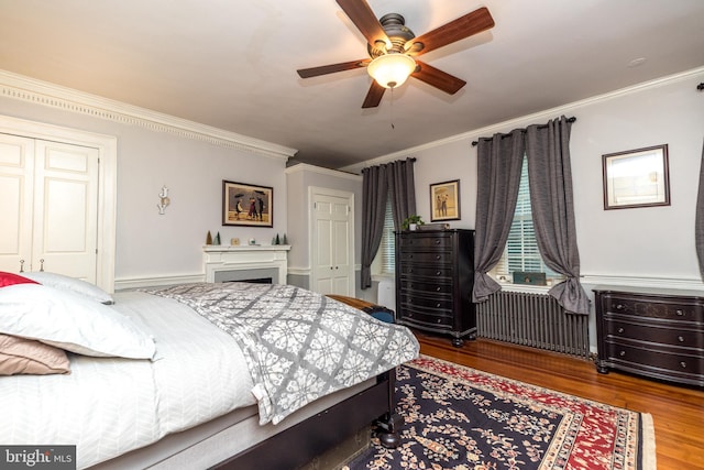 bedroom featuring radiator, ornamental molding, hardwood / wood-style flooring, a closet, and ceiling fan