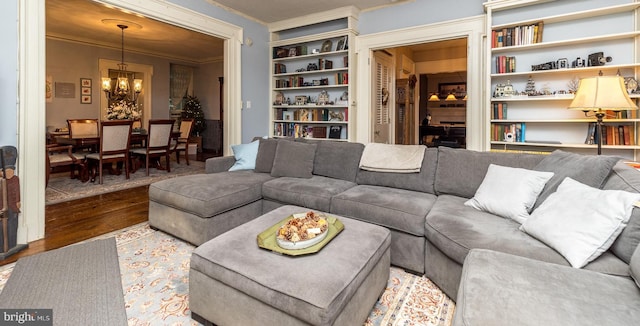 living room featuring ornamental molding, hardwood / wood-style floors, built in features, and a chandelier