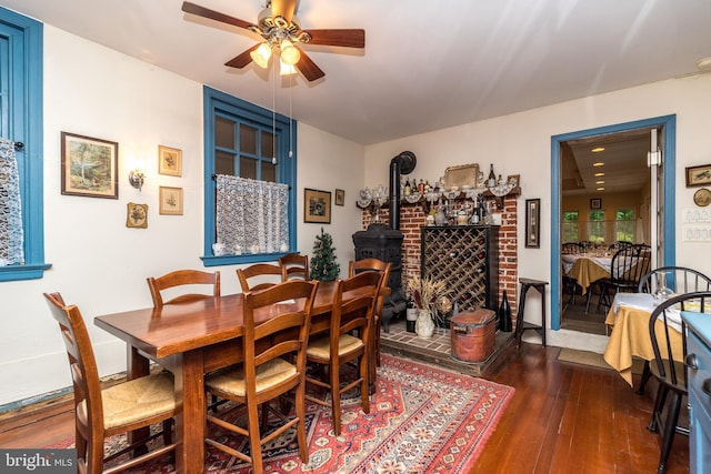 dining space featuring hardwood / wood-style floors, a wood stove, and ceiling fan