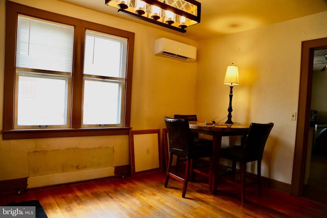 dining space with a wall unit AC, wood-type flooring, and a healthy amount of sunlight