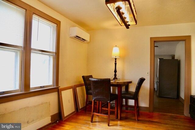 dining area featuring an AC wall unit, hardwood / wood-style flooring, and a healthy amount of sunlight