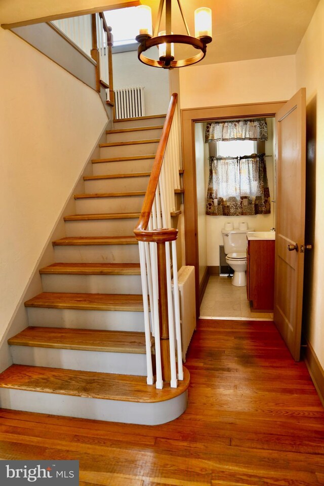 stairway featuring an inviting chandelier and hardwood / wood-style floors