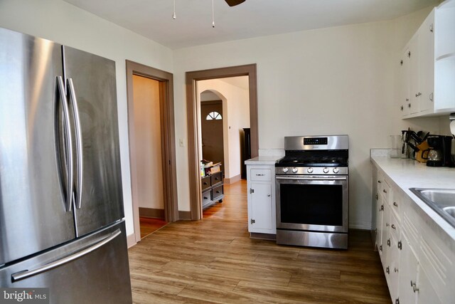 kitchen with dark hardwood / wood-style flooring, radiator heating unit, white cabinetry, and stainless steel refrigerator