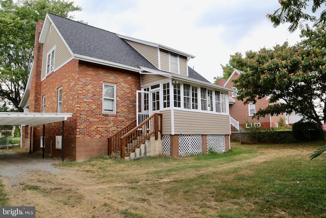 back of property with a yard and a sunroom