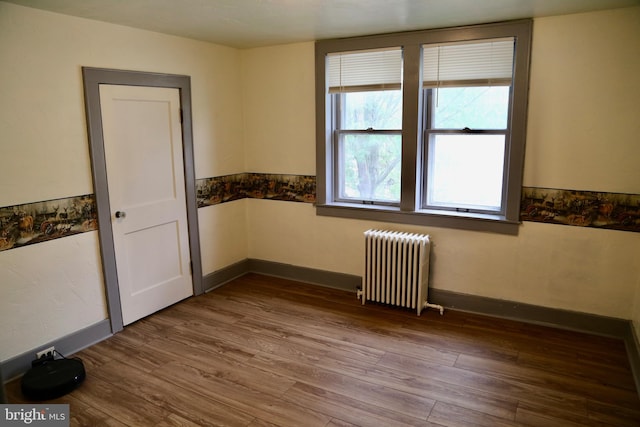 unfurnished room featuring radiator heating unit and wood-type flooring