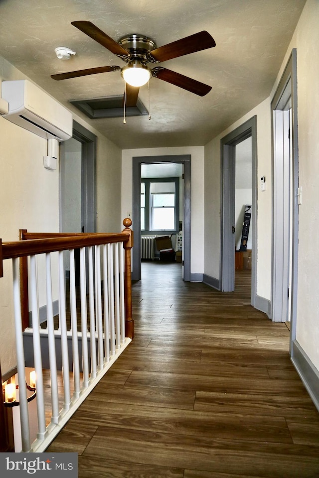 corridor with a wall mounted air conditioner, radiator heating unit, and hardwood / wood-style flooring