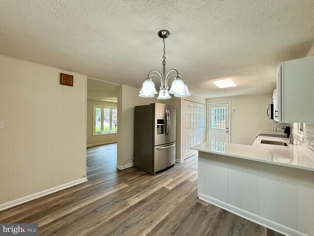 kitchen featuring sink, an inviting chandelier, decorative light fixtures, hardwood / wood-style flooring, and stainless steel appliances