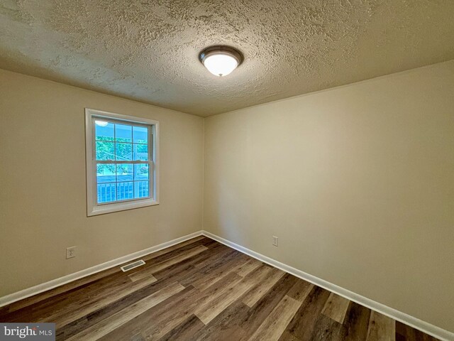 spare room featuring hardwood / wood-style flooring and a textured ceiling