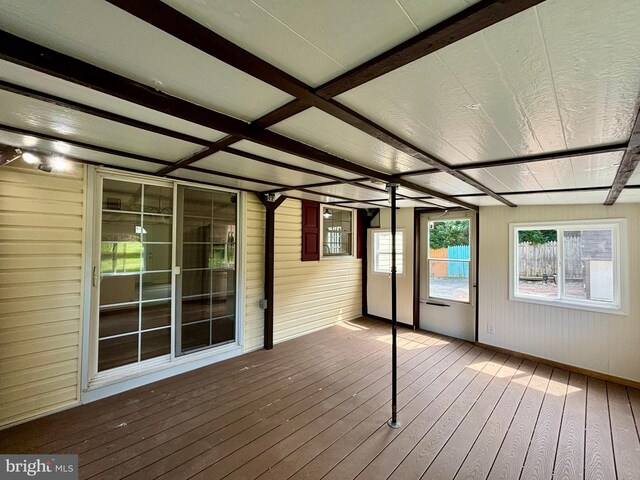 unfurnished sunroom featuring beam ceiling