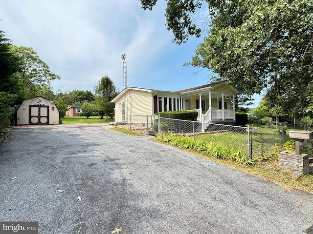 view of front of house with an outbuilding, a fenced front yard, covered porch, a shed, and a front yard