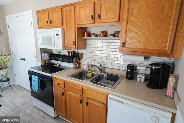 kitchen with sink, light wood-type flooring, tasteful backsplash, and white appliances