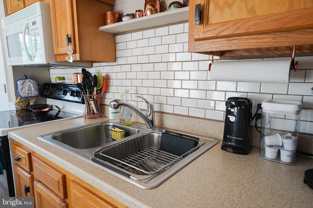 kitchen with sink, electric stove, and backsplash