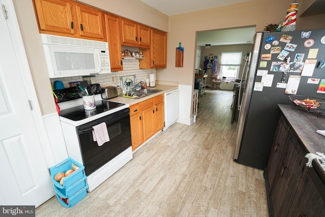 kitchen with light wood-style flooring, white appliances, a sink, light countertops, and brown cabinets