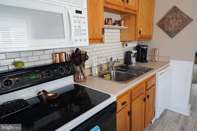 kitchen with sink, light hardwood / wood-style flooring, backsplash, and white appliances