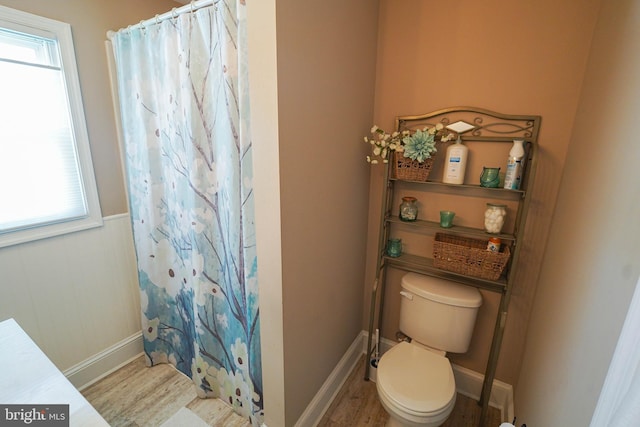 bathroom with a wealth of natural light, toilet, and hardwood / wood-style floors