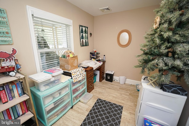 office space with light wood finished floors, visible vents, and baseboards