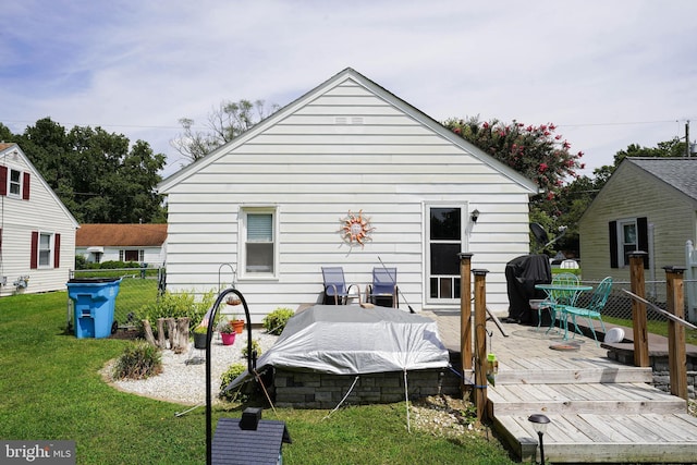 rear view of property with a lawn, a wooden deck, and fence