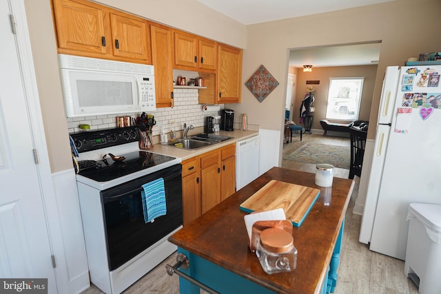 kitchen with light wood-type flooring, backsplash, sink, and white appliances