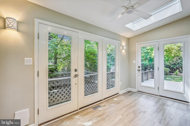 doorway to outside featuring vaulted ceiling with skylight, hardwood / wood-style floors, and ceiling fan