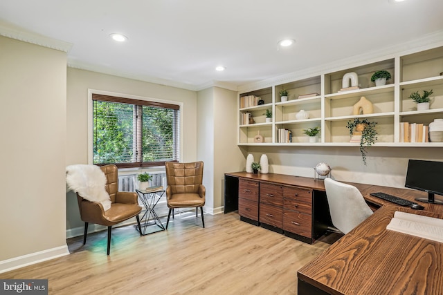 office area with built in desk, light hardwood / wood-style floors, and crown molding