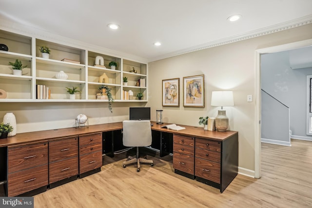 office space with built in desk and light hardwood / wood-style flooring