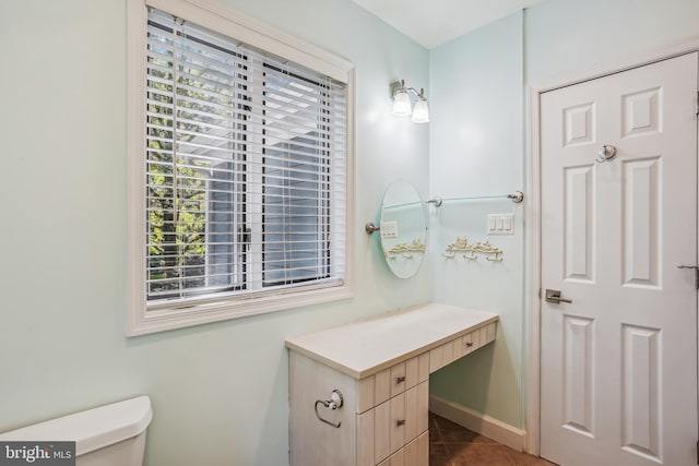 bathroom with a wealth of natural light, toilet, and tile patterned floors