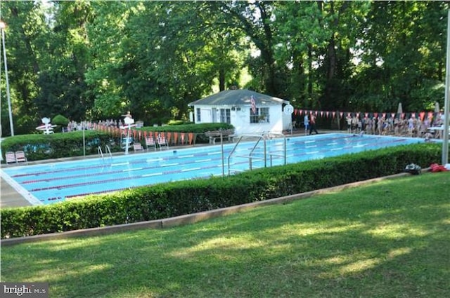 view of swimming pool featuring a lawn and an outbuilding