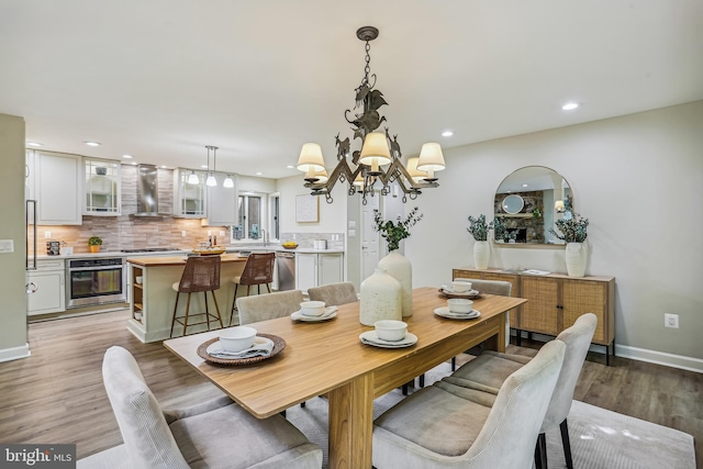 dining area with light hardwood / wood-style flooring, a chandelier, and sink