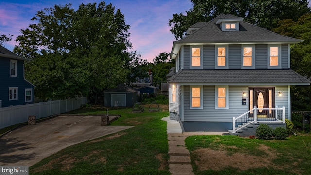 view of front facade featuring a yard, a storage unit, and a patio