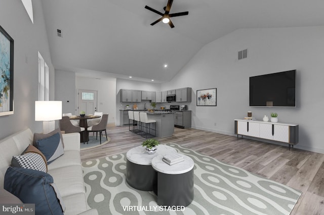 living room with light hardwood / wood-style floors, high vaulted ceiling, and ceiling fan