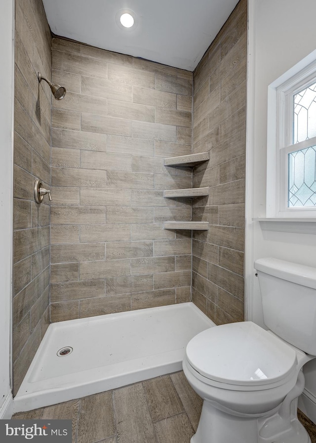 bathroom with a tile shower, hardwood / wood-style floors, and toilet