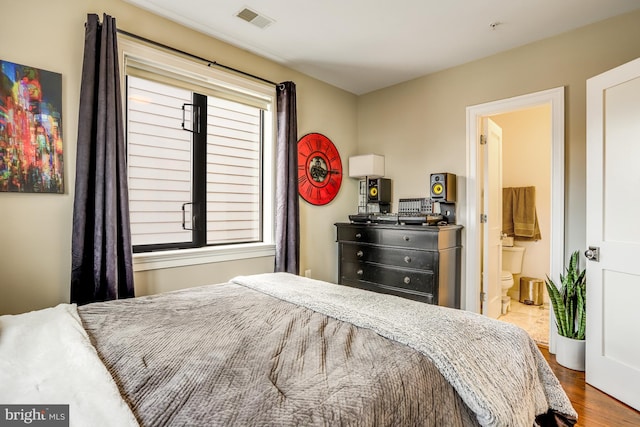 bedroom featuring connected bathroom and hardwood / wood-style flooring