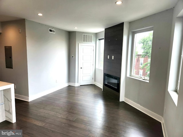 unfurnished living room with dark hardwood / wood-style floors, a fireplace, and electric panel