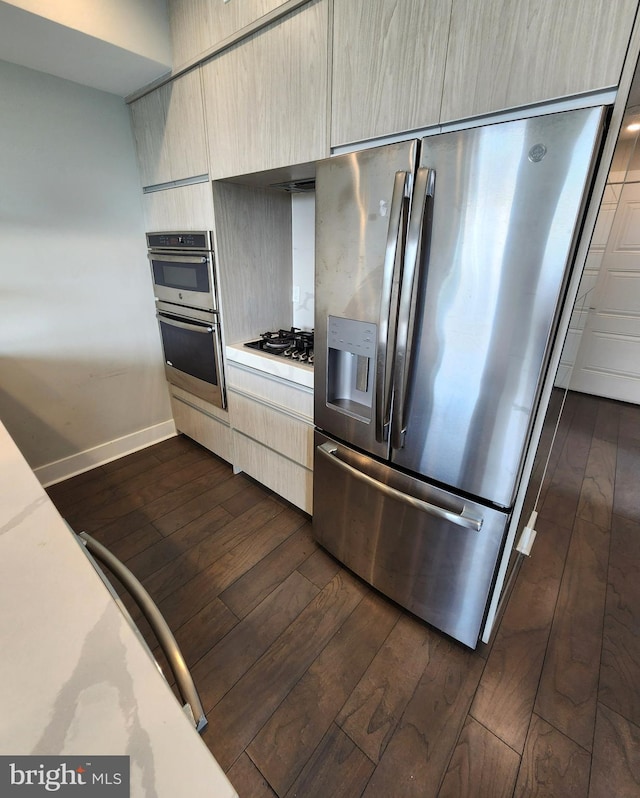 kitchen with appliances with stainless steel finishes, light brown cabinetry, and dark hardwood / wood-style floors