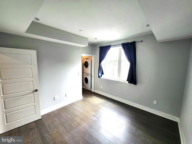 unfurnished bedroom featuring stacked washer / dryer, hardwood / wood-style flooring, and a walk in closet