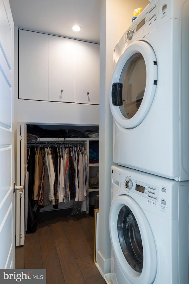 clothes washing area featuring stacked washer / dryer and dark wood-type flooring