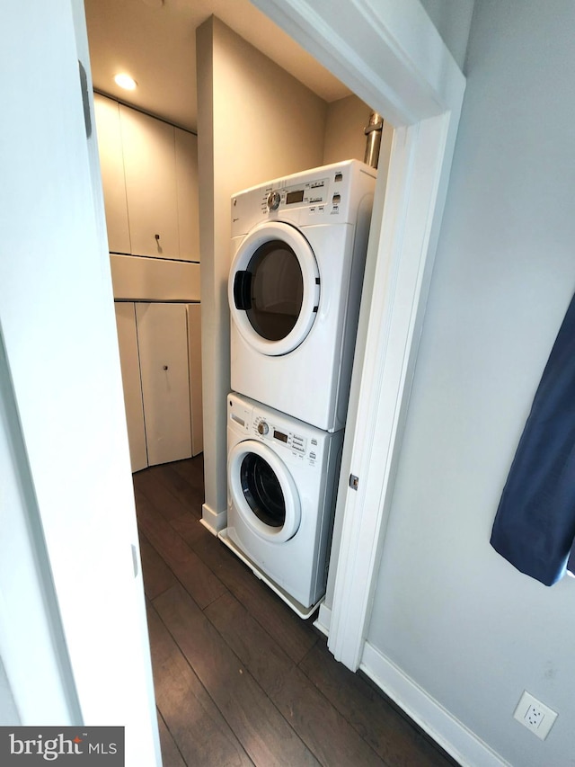 laundry area featuring dark wood-type flooring and stacked washer / dryer