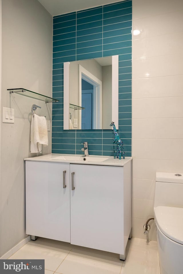 bathroom featuring tile patterned flooring, tile walls, toilet, and vanity