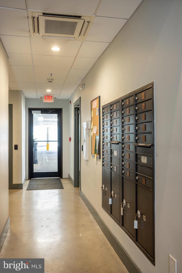 corridor featuring a mail area and a drop ceiling