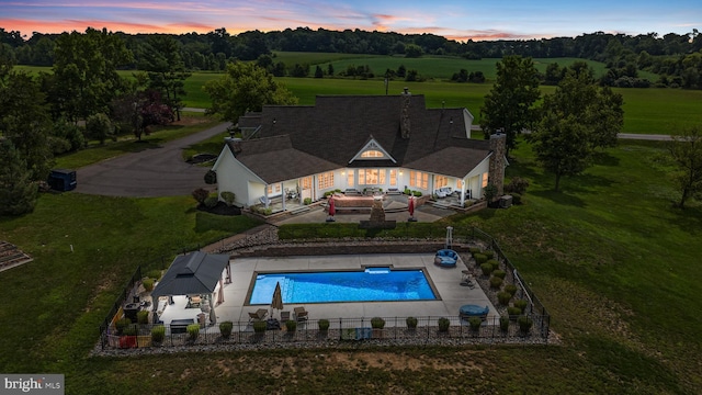 pool at dusk featuring a yard, a gazebo, and a patio