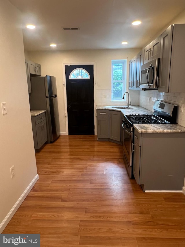 kitchen with light wood-type flooring, appliances with stainless steel finishes, sink, and gray cabinetry