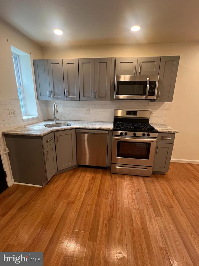 kitchen with sink, light wood-type flooring, gray cabinetry, and appliances with stainless steel finishes