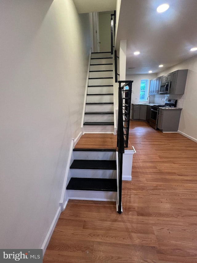 stairs with sink and hardwood / wood-style floors