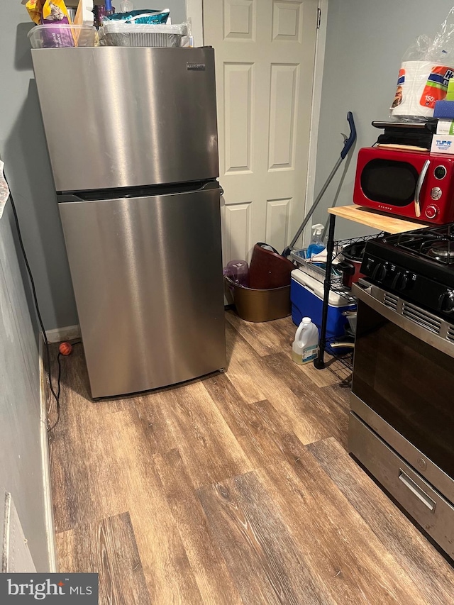 kitchen with appliances with stainless steel finishes and hardwood / wood-style floors