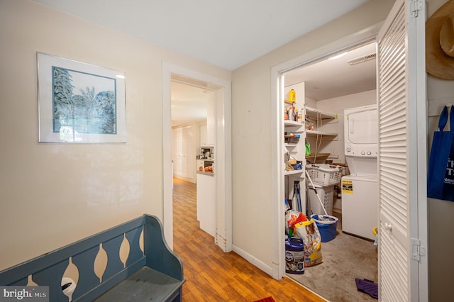 corridor with stacked washer / dryer and wood-type flooring